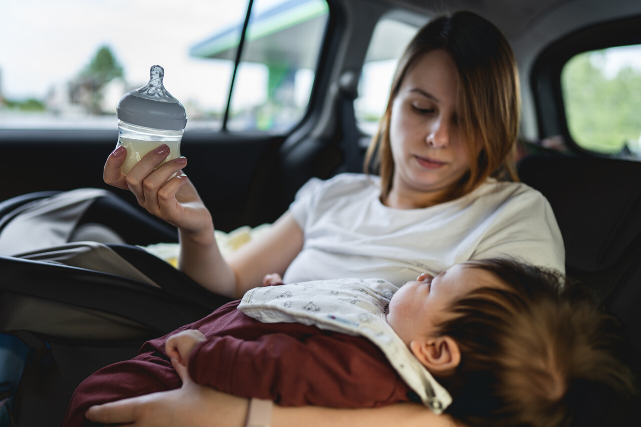 Image of woman in car feeding baby with bottle